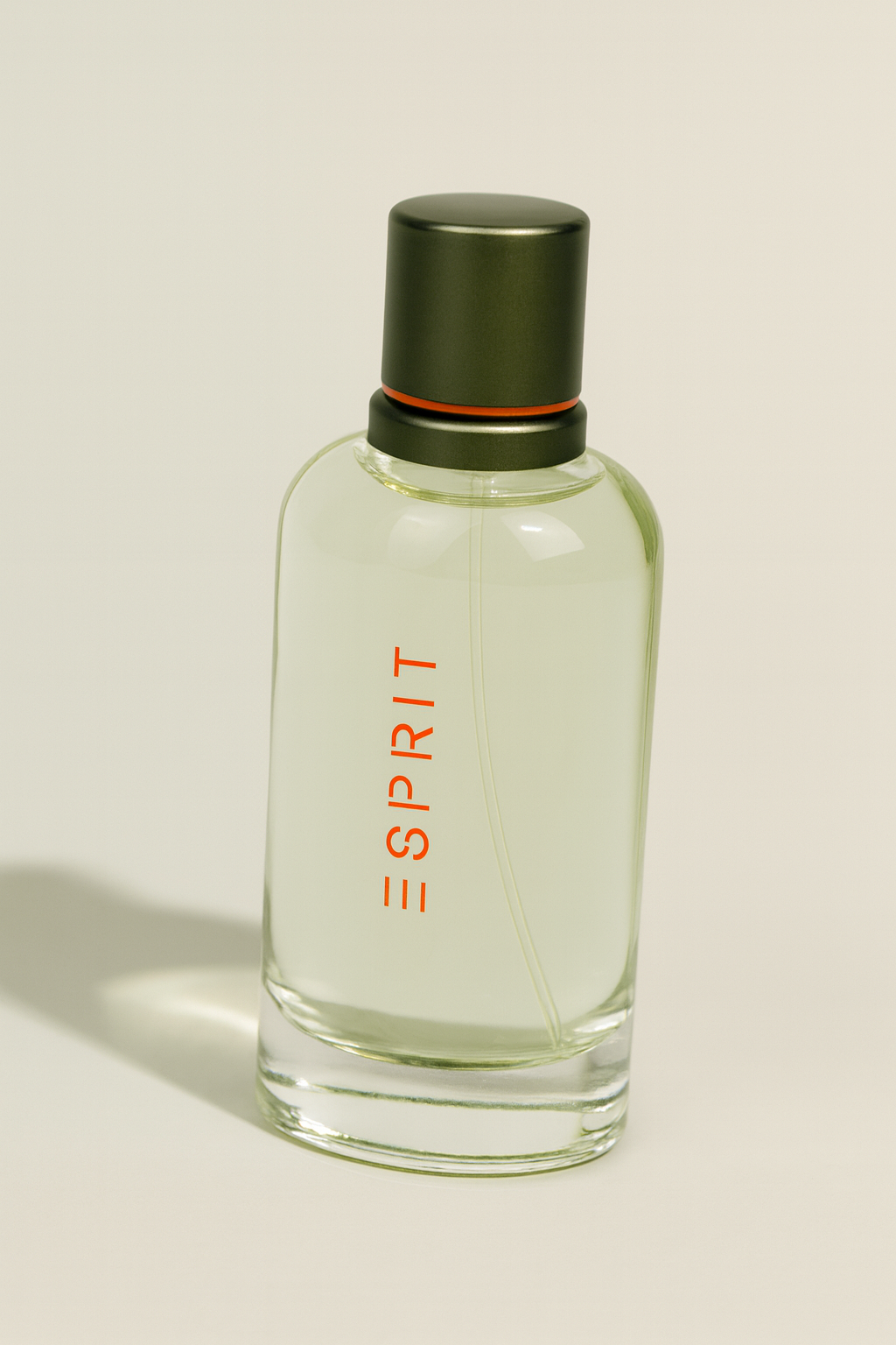 Ein rechteckiges Eau de Toilette Flakon von Esprit, durchsichtig mit hellgrünlicher Flüssigkeit, einem silberfarbenen Deckel mit oranger Linie und vertikalem roten „ESPRIT“-Schriftzug auf der Vorderseite. Das Flakon ist leicht nach hinten gekippt, vor neutralem Hintergrund mit weichem Schatten.