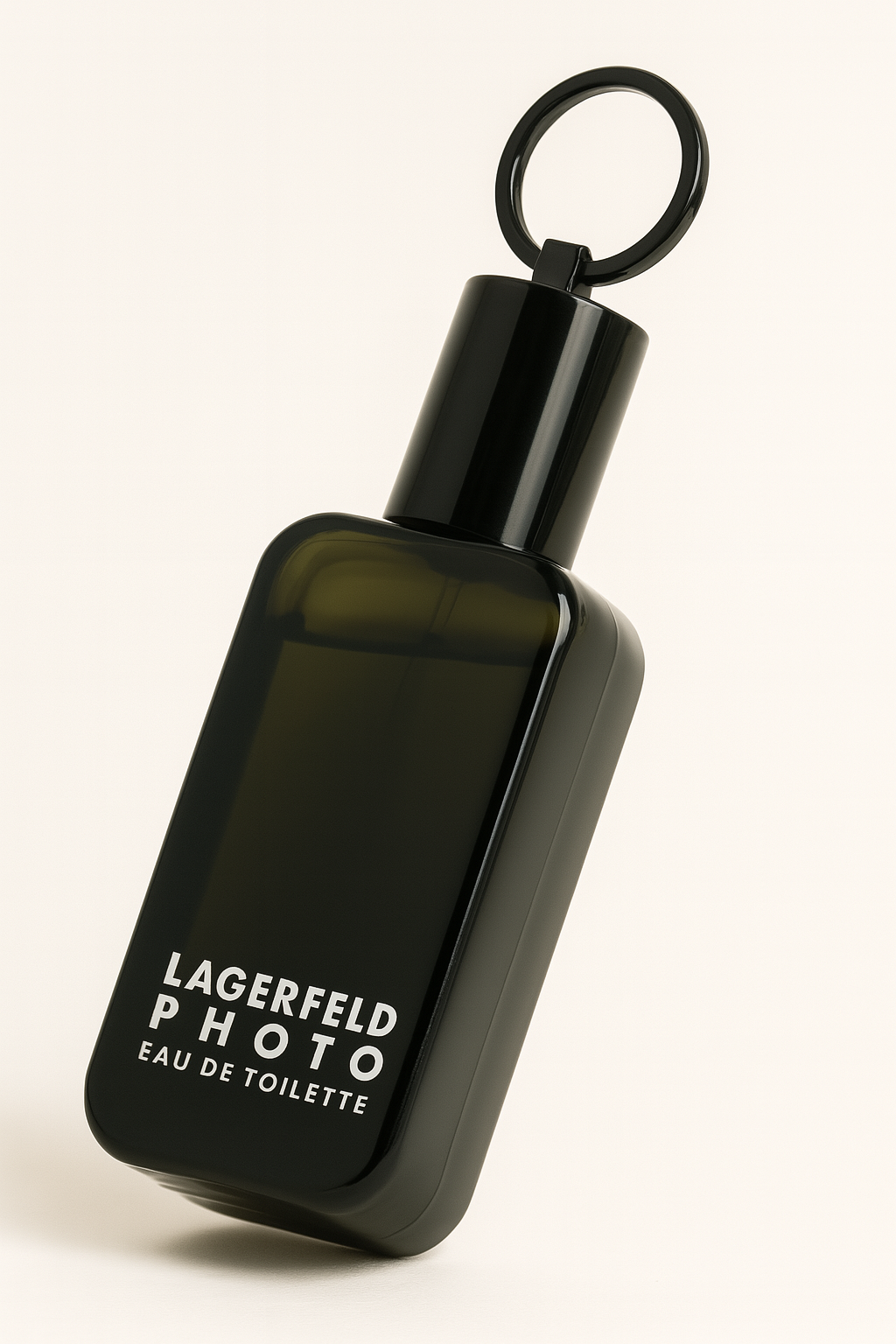 Ein tiefdunkles, eckiges Parfumflakon des „Lagerfeld PHOTO Eau de Toilette“ steht leicht nach hinten geneigt auf einem hellen, neutralen Hintergrund. Die weiße Aufschrift auf der Vorderseite ist klar lesbar. Der auffällige schwarze Deckel mit integriertem Metallring verleiht dem Flakon einen ikonischen Charakter. Ein weicher Schatten fällt dezent nach rechts unten.