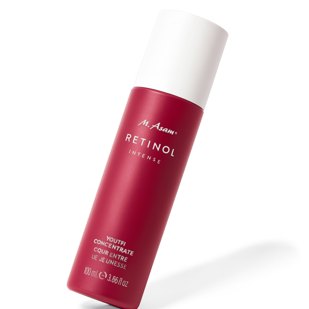 Eine bordeauxrote Pumpflasche der M. Asam Retinol Intense Youth Concentrate (100 ml) liegt schräg nach hinten geneigt auf einem weißen Hintergrund. Der weiße Deckel kontrastiert mit dem roten Flaschenkörper, auf dem die weiße Schrift mit Produktnamen und Details gut sichtbar ist. Ein weicher Schatten betont die Tiefe und Perspektive.