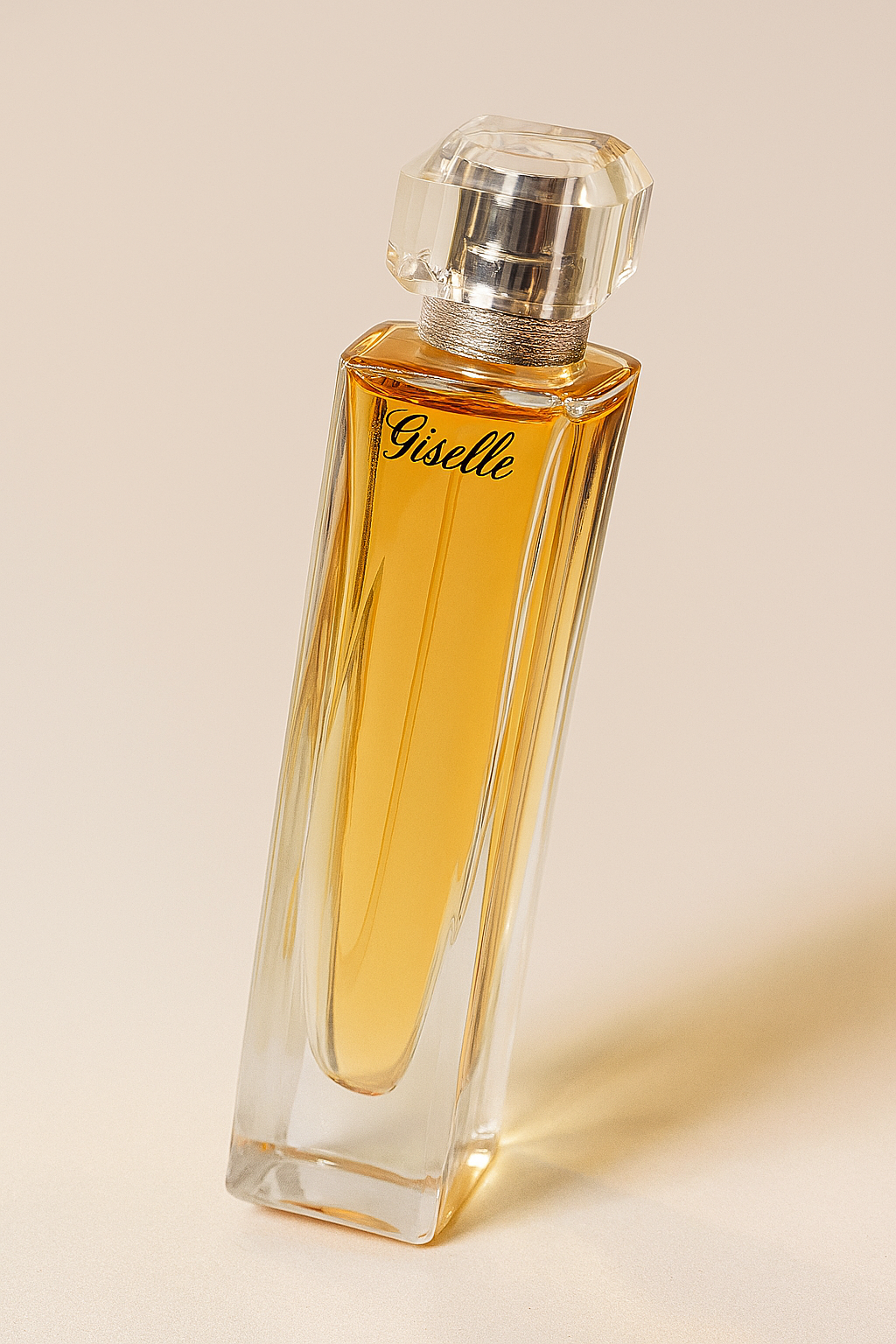 Ein stilvolles Parfumflakon mit der Aufschrift „Giselle“, leicht zur Seite gekippt dargestellt. Die Flasche ist hoch, transparent und mit einem warm-goldenen Duft gefüllt, gekrönt von einem facettierten, kristallklaren Verschluss. Der neutrale Hintergrund sorgt für einen weichen, natürlichen Schatten.