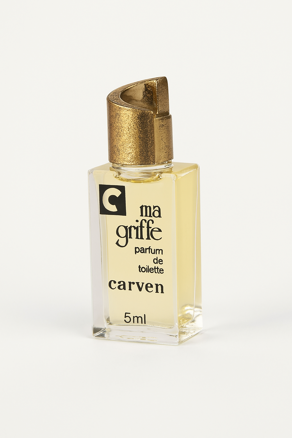 Ein digital fotografiertes Parfumfläschchen von „ma griffe“ von Carven (5 ml) steht leicht nach hinten geneigt auf einem neutralen, hellen Untergrund. Das eckige Glasflakon mit goldener Kappe zeigt deutlich die schwarze Aufschrift auf der Vorderseite. Ein weicher, natürlicher Schatten verstärkt die Tiefenwirkung.