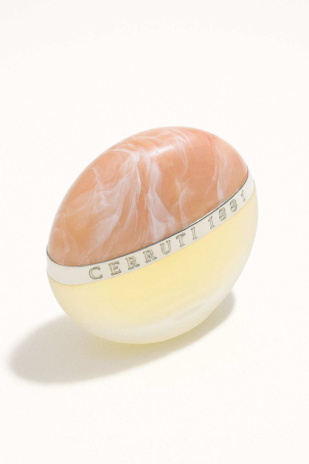 Ein stilisiertes Parfumflakon von Cerruti 1881 mit halbkugelförmigem Design. Die obere Hälfte ist marmoriert in Pfirsichrosa, die untere Hälfte matt-transparent. Ein silbernes Band mit der Prägung „CERRUTI 1881“ verläuft horizontal durch die Mitte. Der Hintergrund ist neutralweiß, das Flakon wirft einen weichen, natürlichen Schatten.