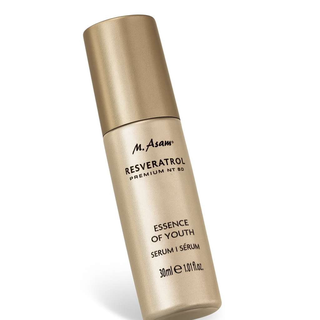 Eine goldfarbene, zylindrische Pumpflasche des M. Asam Resveratrol Premium NT50 Essence of Youth Serums liegt leicht schräg nach hinten gekippt auf weißem Hintergrund. Der Markenname und die Produktbeschreibung in schwarzer Schrift sind gut sichtbar, die Flasche wirft einen sanften Schatten.