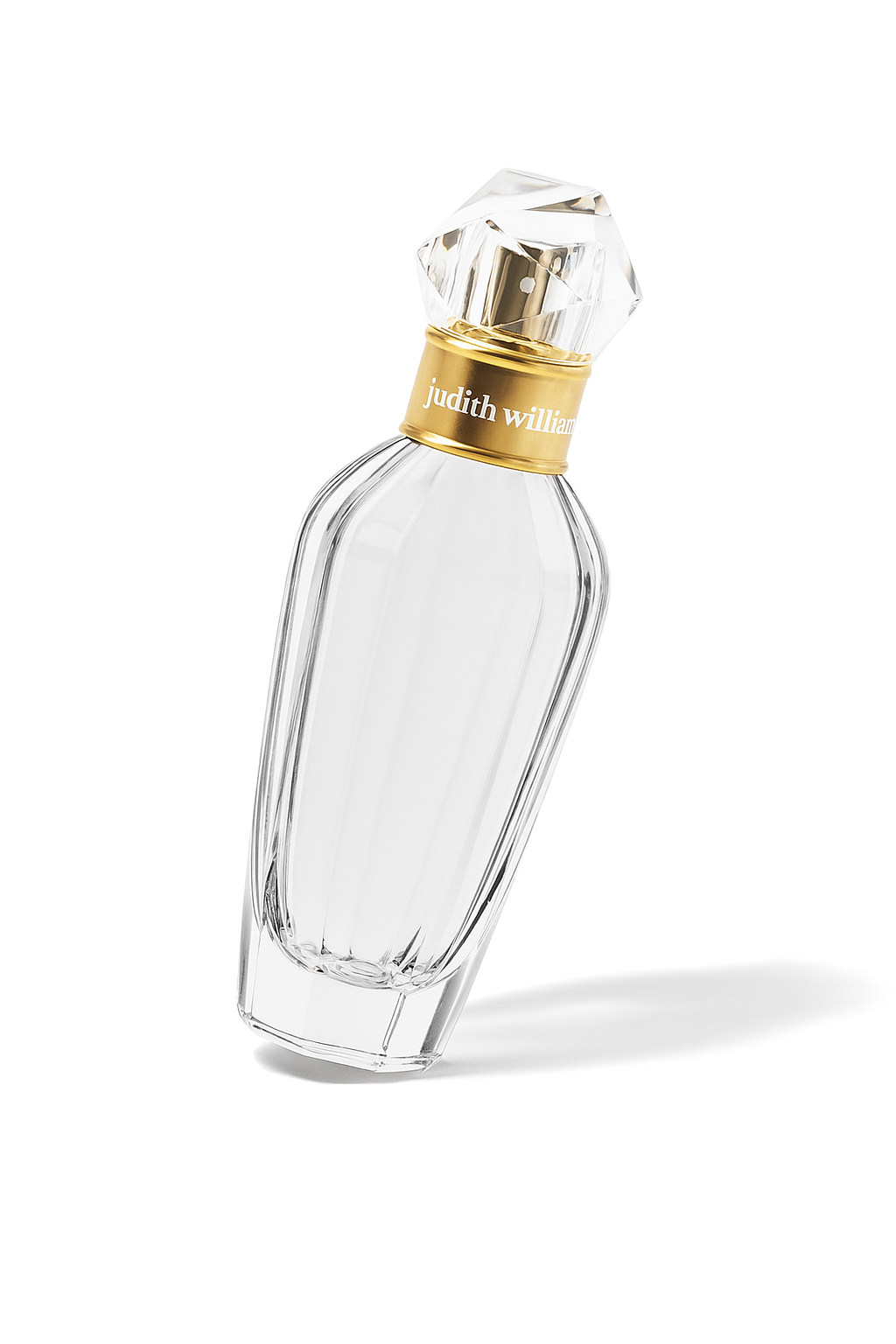 Ein Parfümflakon von Judith Williams mit goldfarbenem Sprühkopf und kristallartigem Verschluss steht leicht nach hinten und zur Seite geneigt auf weißem Untergrund. Die zylindrische, elegant gerillte Glasform wirft einen weichen, natürlichen Schatten.