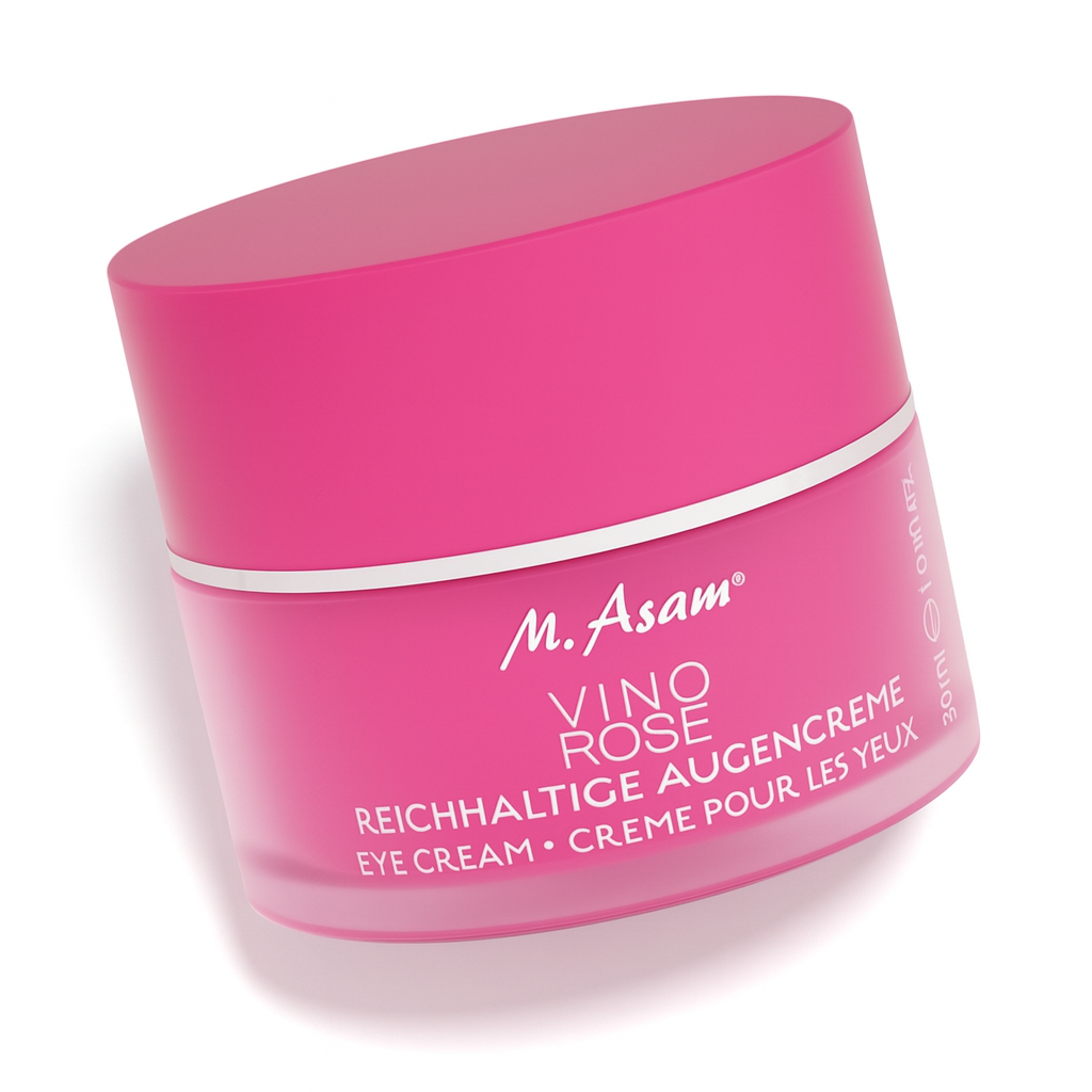 Ein pinkfarbener Tiegel der M. Asam VINO ROSE Reichhaltigen Augencreme liegt leicht schräg nach hinten gekippt auf weißem Hintergrund. Der Deckel ist ebenfalls pink mit silbernem Rand, die weiße Beschriftung auf der Vorderseite ist gut lesbar, und der Tiegel wirft einen weichen Schatten.