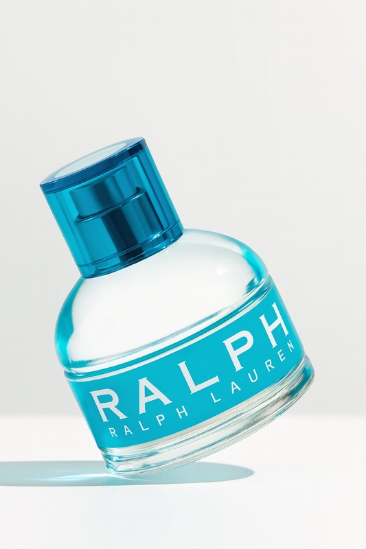 Ein rundes, türkisblaues Flakon des Parfums Ralph von Ralph Lauren, leicht nach hinten gekippt. Der weiße Schriftzug ‚RALPH Ralph Lauren‘ ist auf der Vorderseite gut sichtbar. Das Flakon steht auf neutralem Hintergrund und wirft einen sanften Schatten.