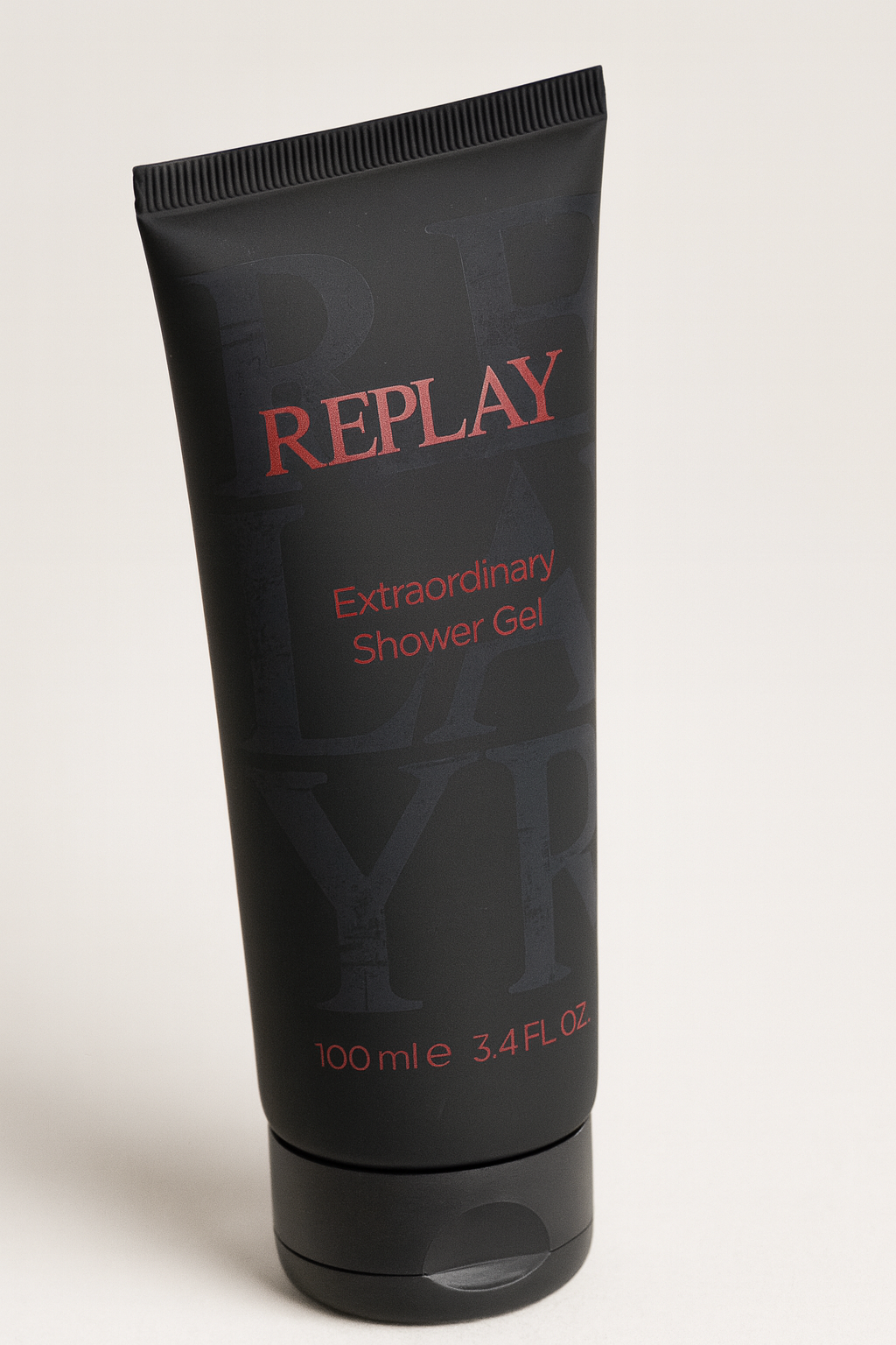 Schwarze Tube Replay Extraordinary Shower Gel mit roter Aufschrift, leicht nach hinten gekippt und mit weichem Schatten auf neutralem Hintergrund.