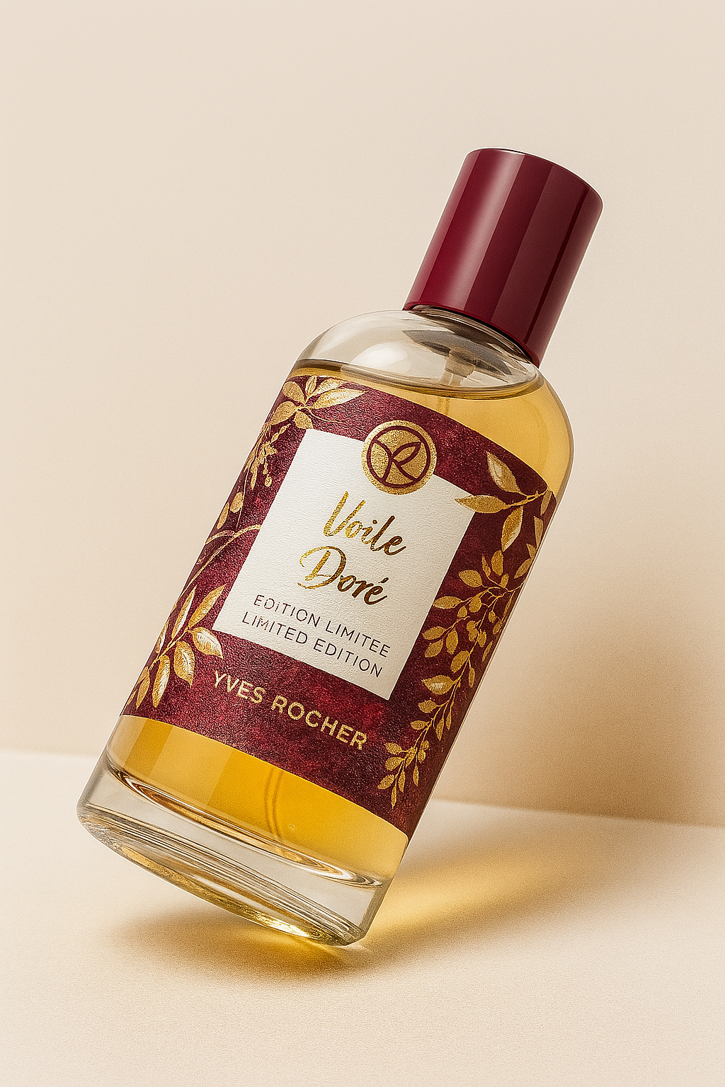 Ein Yves Rocher „Voile Doré“ Eau de Toilette Flakon liegt leicht nach hinten geneigt auf einem sanften, beigefarbenen Hintergrund. Der elegante Glasflakon mit goldgelber Flüssigkeit und burgunderfarbener Verschlusskappe wirft einen weichen Schatten. Die florale Etikettierung ist gut lesbar und zeigt goldene Zweige auf dunkelrotem Grund.