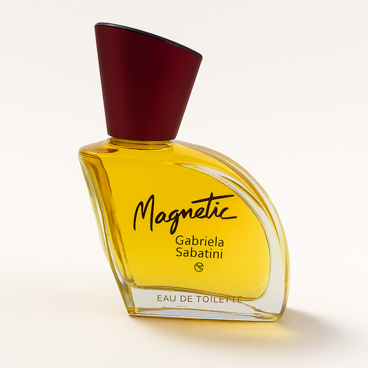 Ein stilvolles, leicht seitlich gekipptes Parfümflakon von Gabriela Sabatini „Magnetic“ mit goldgelber Flüssigkeit, burgunderrotem Deckel und schwarzer Aufschrift auf hellem, neutralem Hintergrund. Ein weicher, natürlicher Schatten unterstreicht die elegante Form des Flakons.