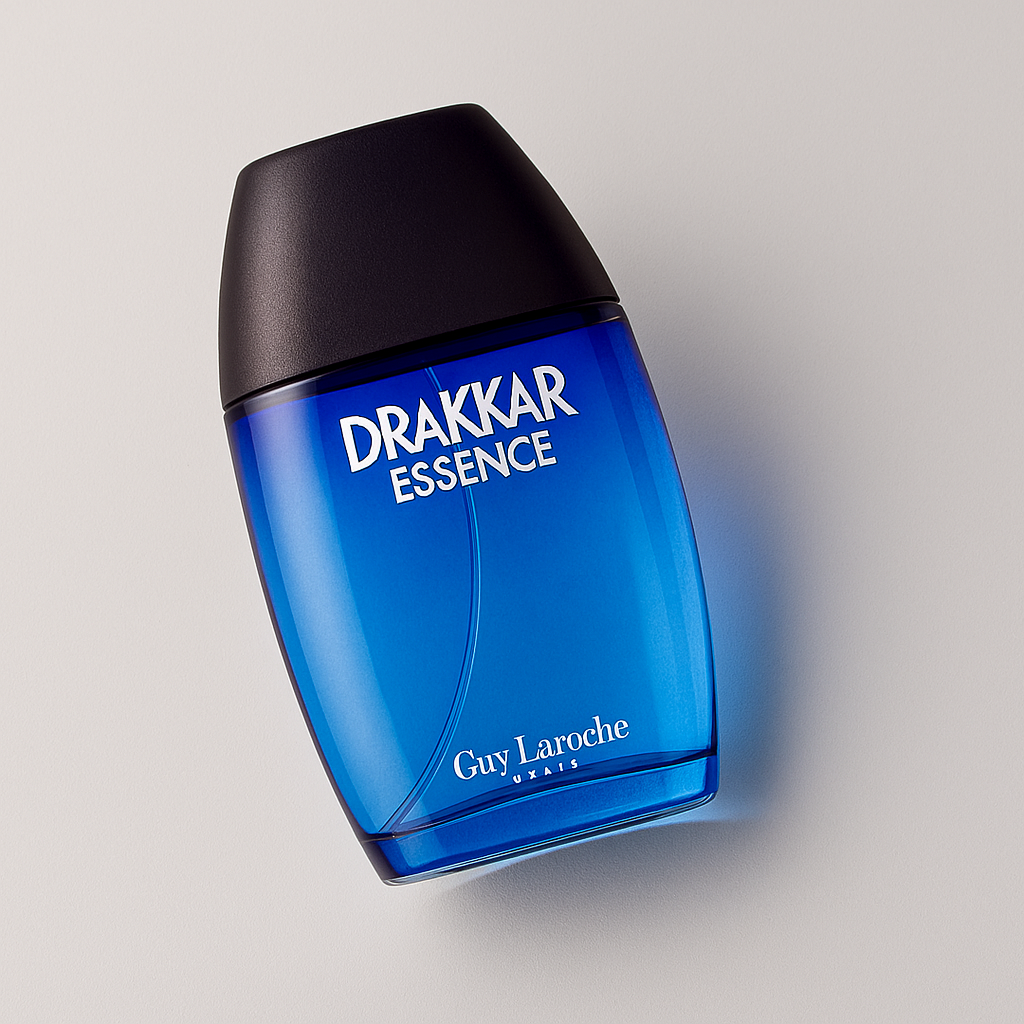 Ein bläuliches Parfumflakon von Drakkar Essence von Guy Laroche liegt leicht seitlich gekippt auf einer neutralen Fläche. Die Vorderseite mit weißer Schrift ist gut lesbar. Das Licht erzeugt einen sanften Schatten und betont die elegante Kurve der Flasche und den schwarzen Deckel.