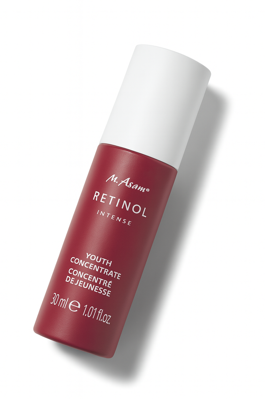 Eine bordeauxrote Pumpflasche der M. Asam Retinol Intense Youth Concentrate liegt leicht nach hinten geneigt auf einem weißen Hintergrund. Der weiße Deckel kontrastiert mit dem dunklen Flaschenkörper, auf dem die weiße Schrift mit Produktnamen und Details klar sichtbar ist. Ein weicher Schatten sorgt für Tiefe und Perspektive.